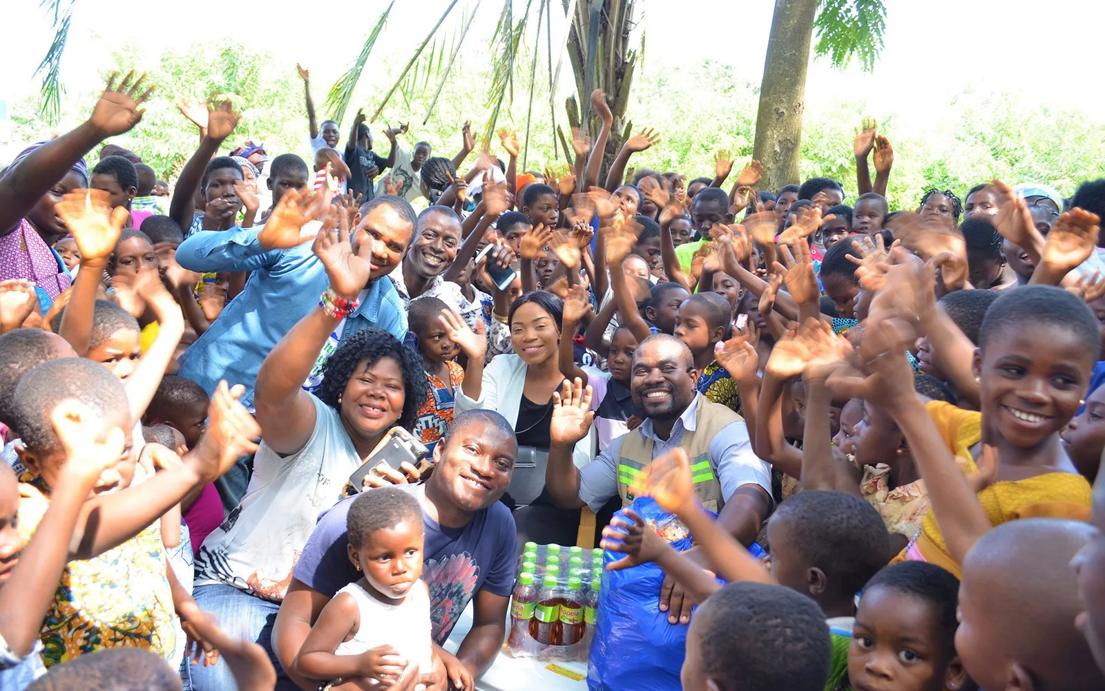 A woman drinking from a newly drilled borehole while a crowd watches.